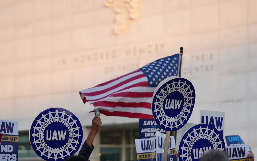 UAW Members Marching with US Flag in Background